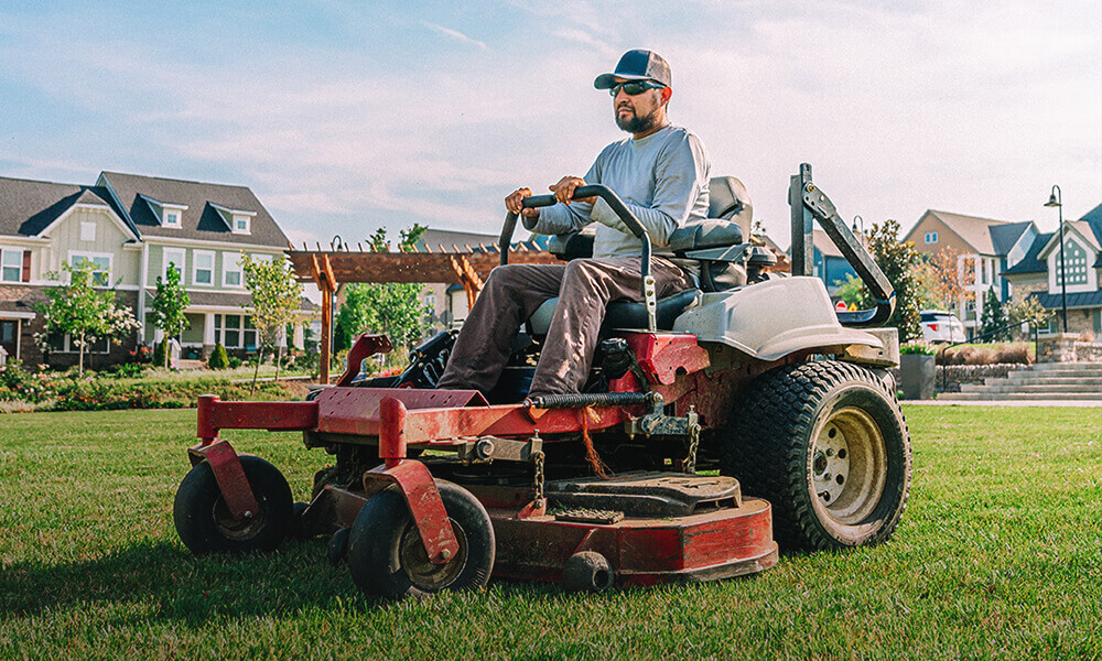 Man driving a riding lawnmower to cut the grass