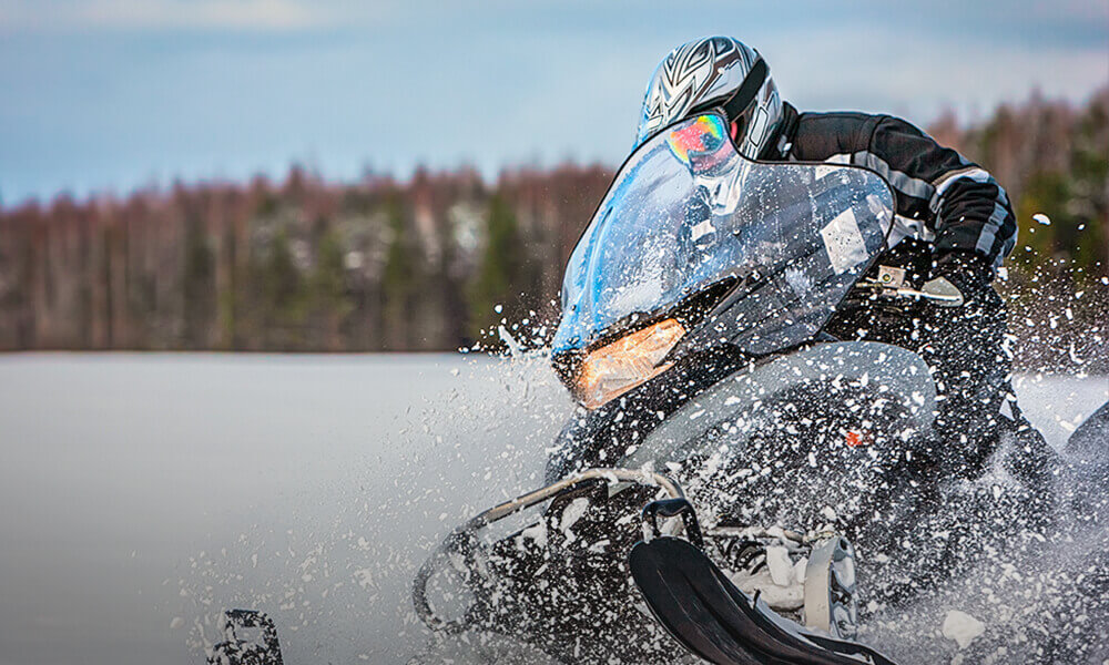 Person driving a snowmobile on a trail in winter